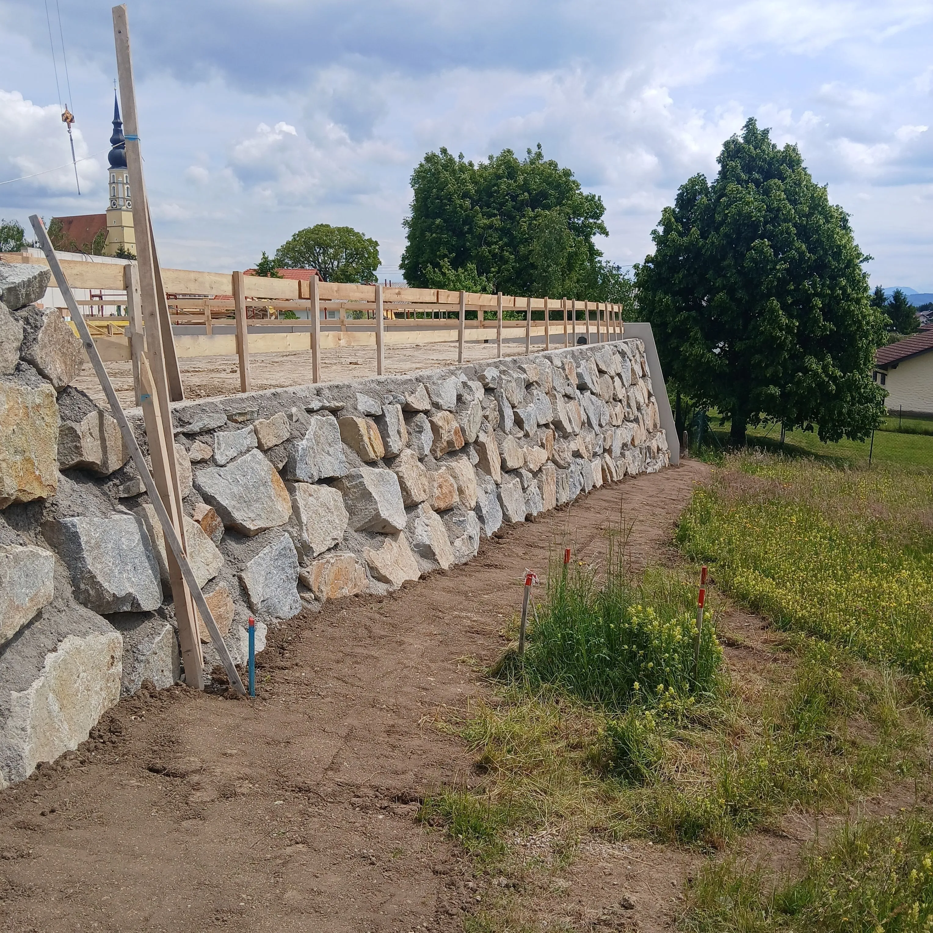 Geschlichtete Natursteinmauer entlang einer abgegrabenen Böschung
