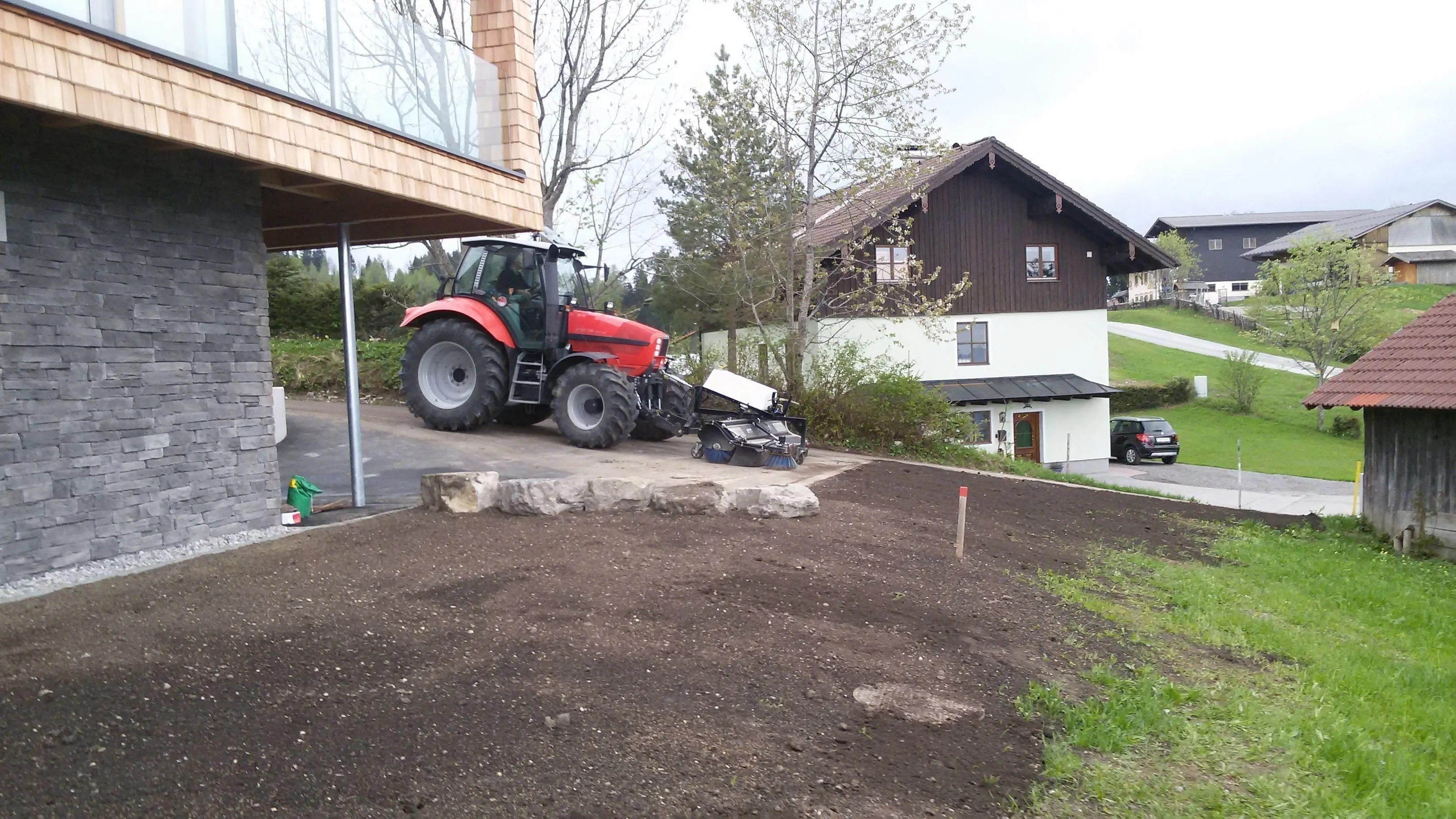Frisch humusierte Fläche vor einem Einfamilienhaus, vorbereitet für die Rasenansaat