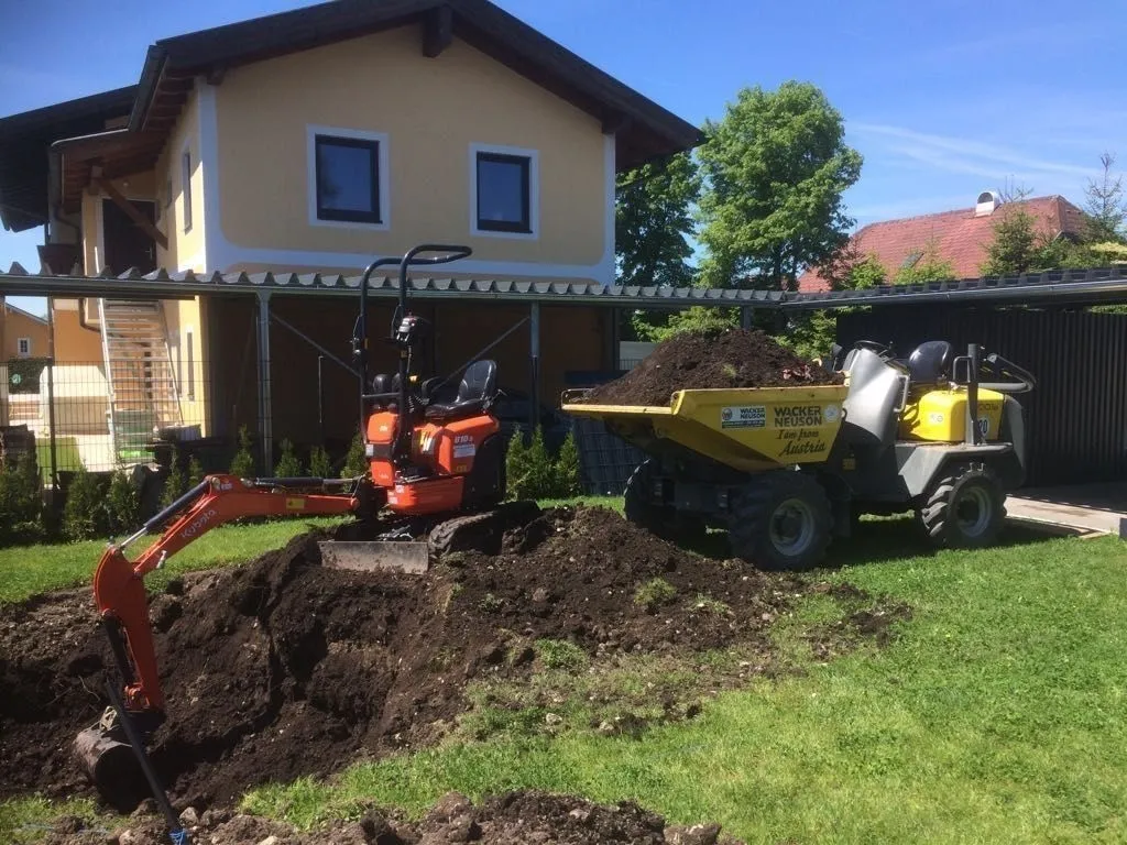 Minibagger und Raddumper bei Humusarbeiten in einem Hausgarten