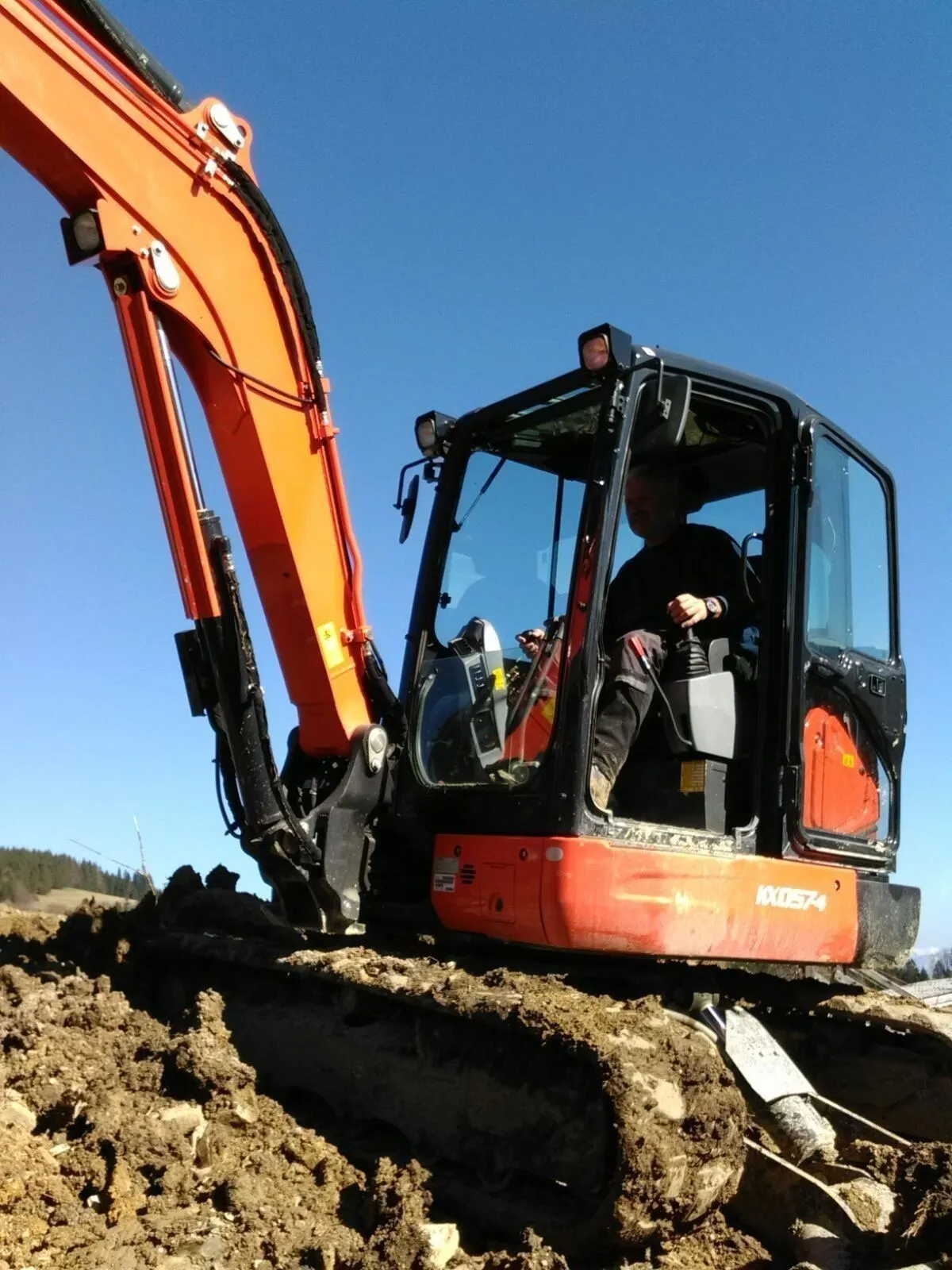 Kubota-Bagger mit Fahrer aus der Froschperspektive vor blauem Himmel