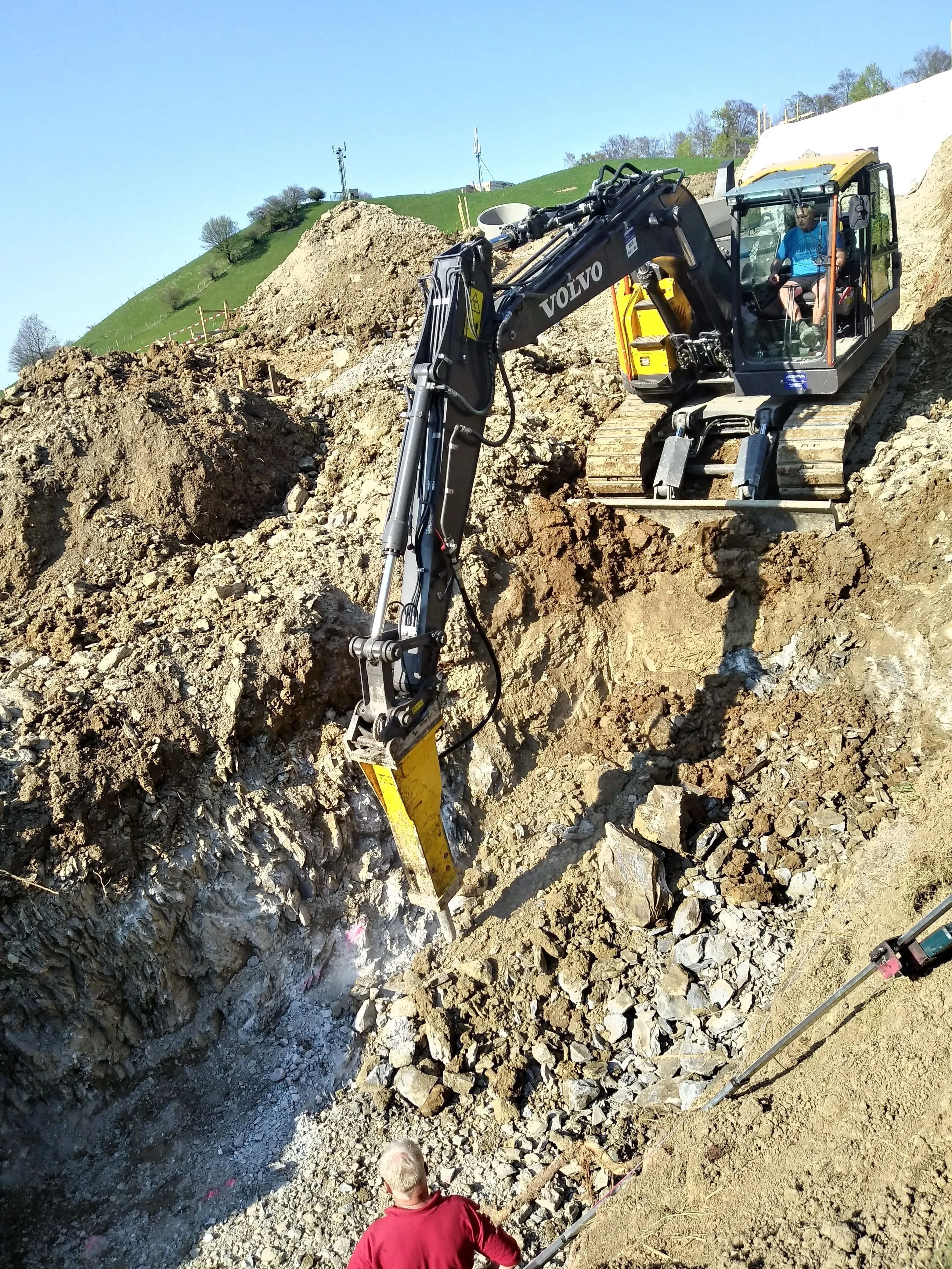 Bagger mit Hydraulikhammer bricht Fels in einer Baugrube