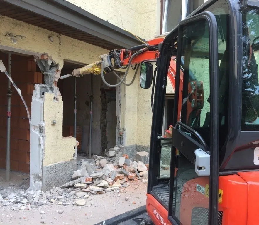 Minibagger mit Hydraulikmeißel bricht eine Wandöffnung