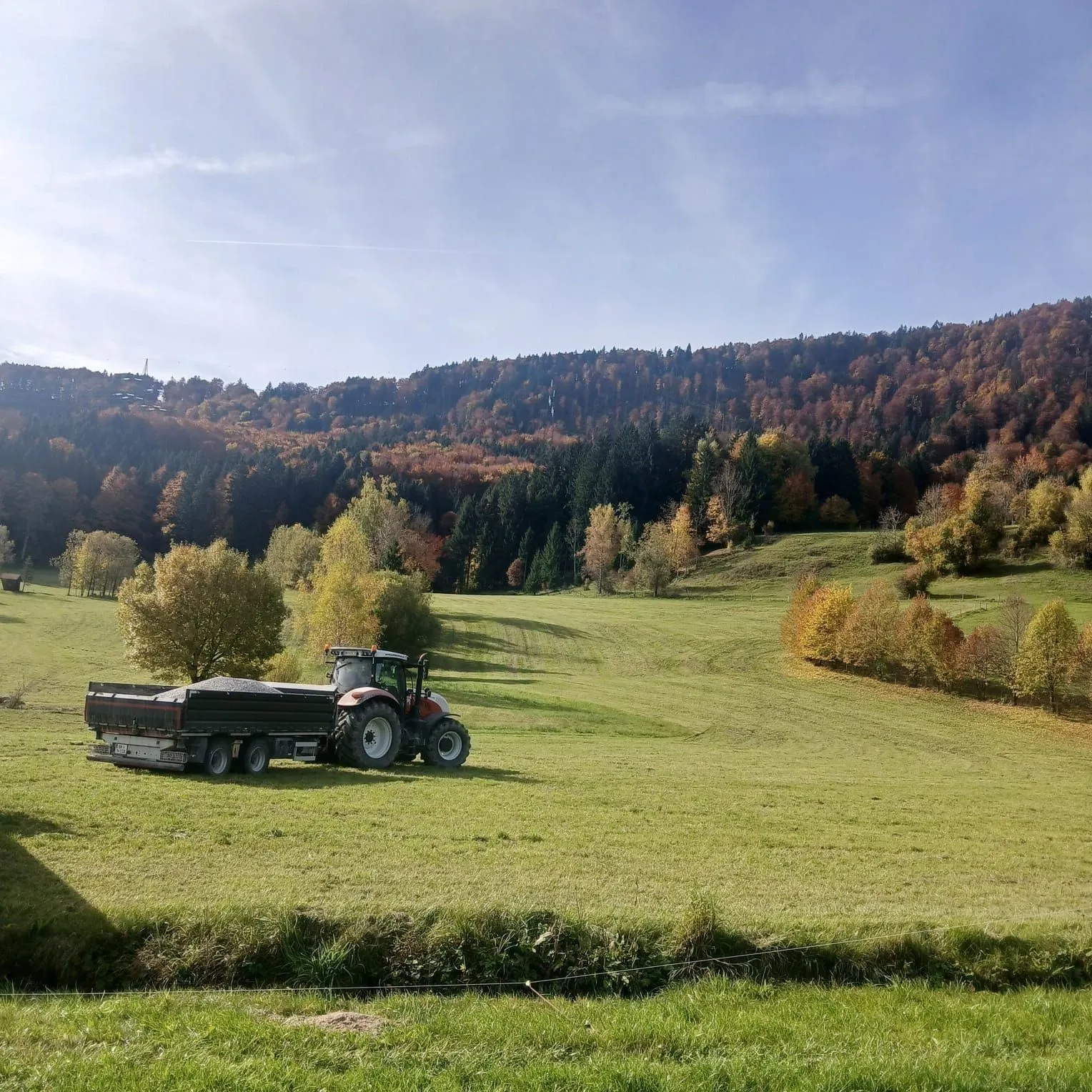 Traktor mit beladenem Dreiseitenkipper voll Schotter