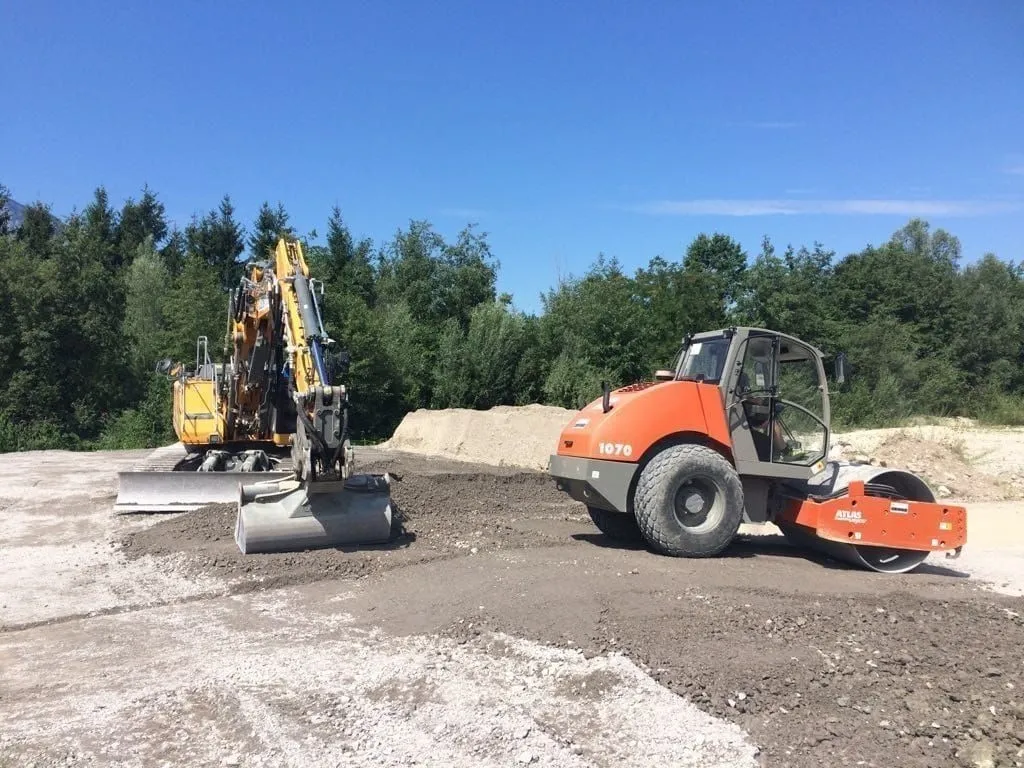 Bagger und Walze auf frisch geschottertem Planum